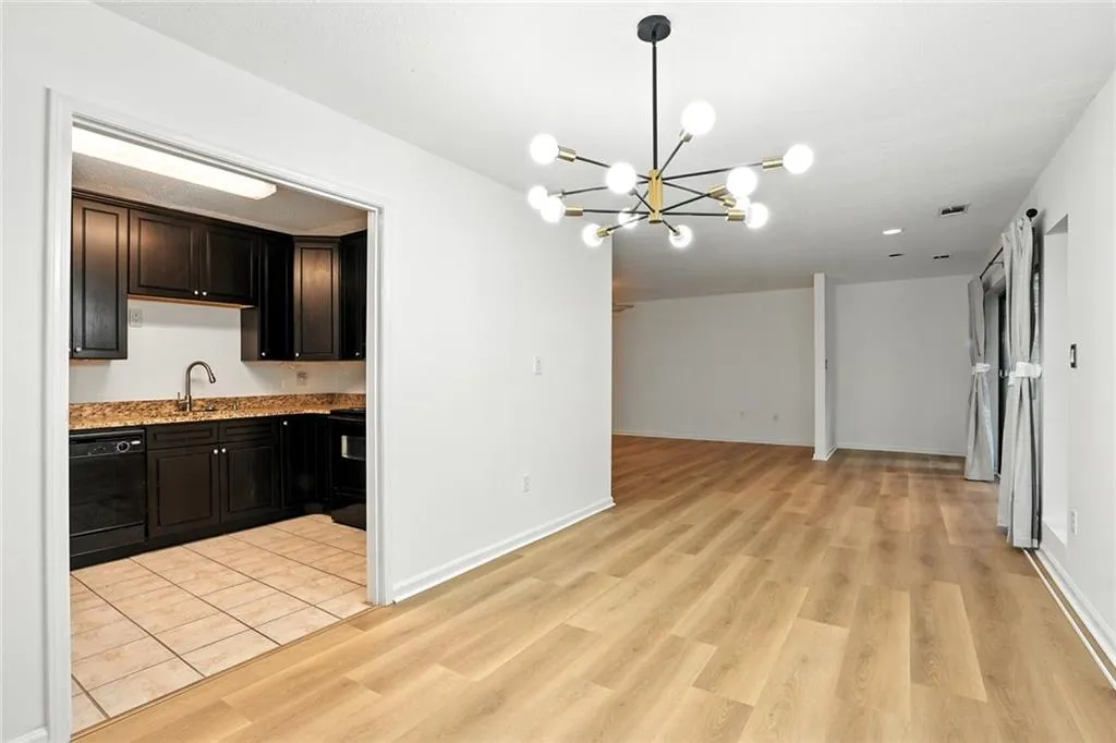 Kitchen featuring a chandelier, open floor plan, black dishwasher, and light wood finished floors