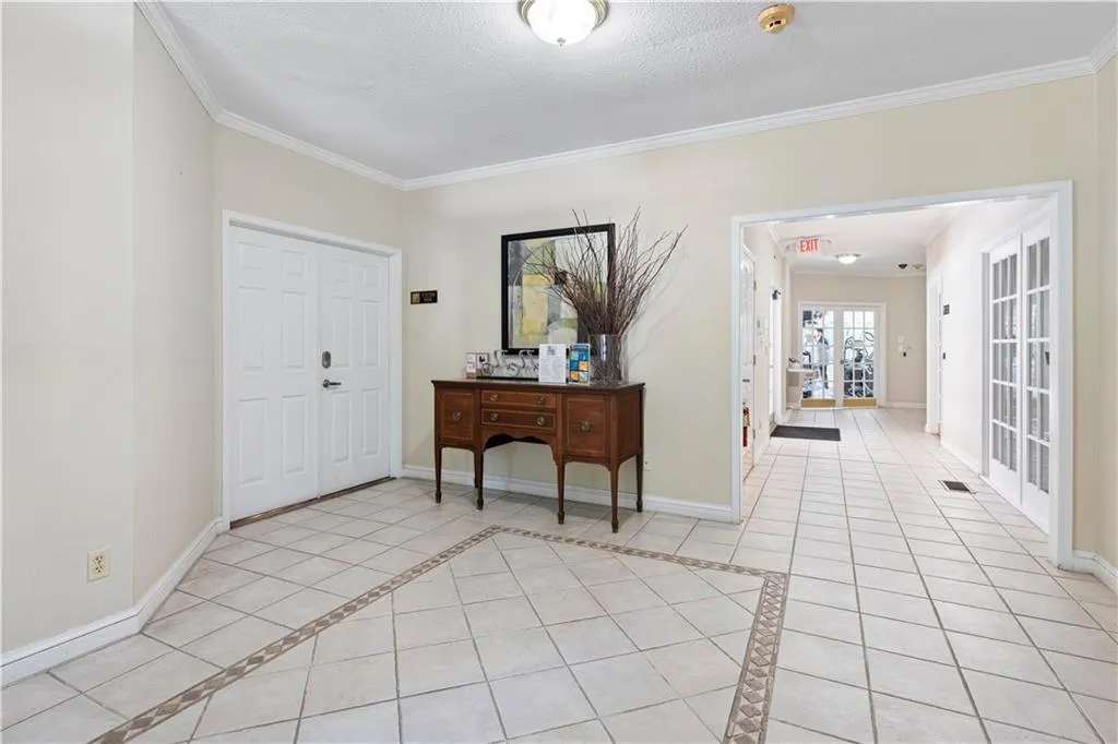 Entryway with light tile patterned floors, ornamental molding, inlaid floor details, and a textured ceiling