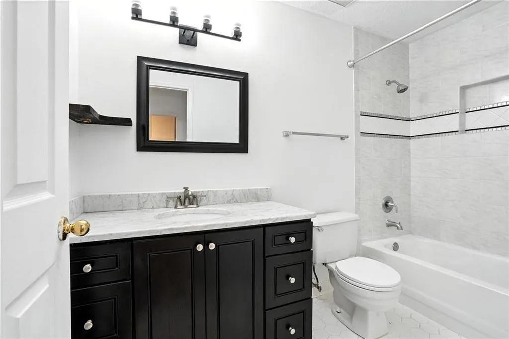 Bathroom with vanity, shower / washtub combination, tile patterned flooring, and a textured ceiling