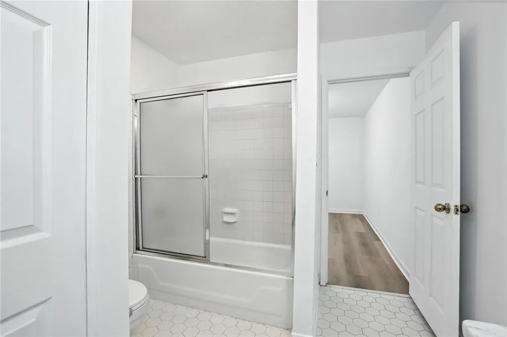 Full bath with enclosed tub / shower combo and tile patterned floors