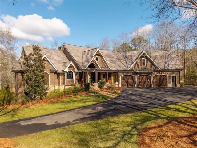 Craftsman-style residence featuring a multi-gable roofline, stone veneer accents, and dark wood siding