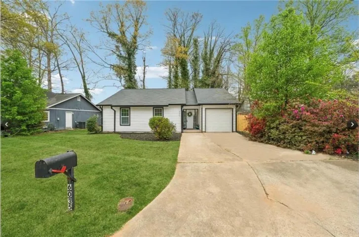 Ranch-style home featuring a front lawn, concrete driveway, and an attached garage