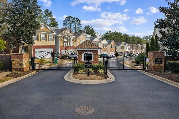 The property features a gated entrance with decorative metal gates and stone pillars, leading to a community of townhomes