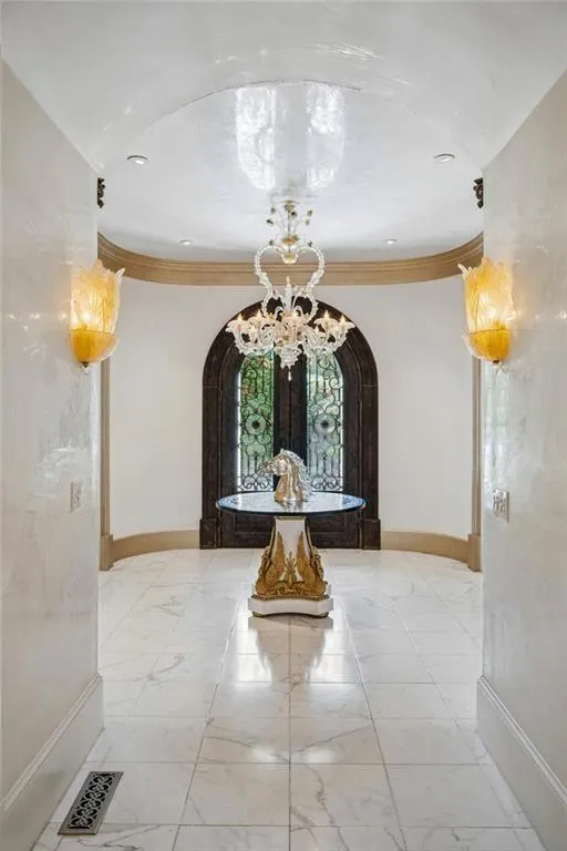 Venetian plaster walls, Murano sconces, and marble floors lead the way to a custom iron and glass entry.