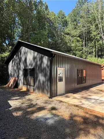 Modern metal-clad structure featuring corrugated steel siding in charcoal and rust tones, a pitched roofline, and a concrete foundation