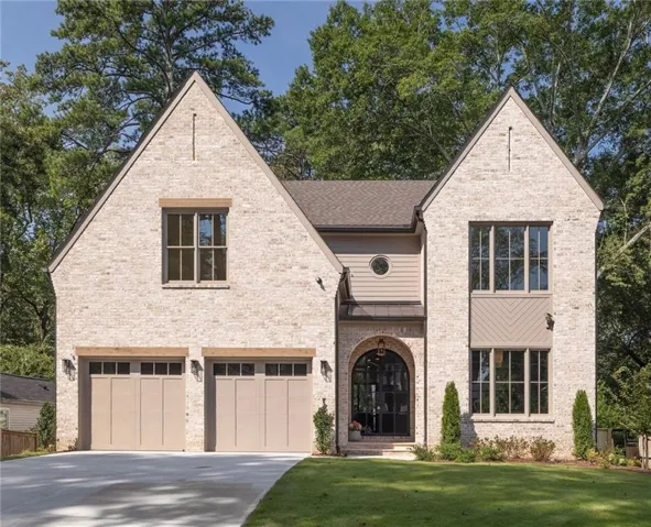 Brick exterior with stone accents, arched entryway with a glass-paneled door, two-car garage, and a concrete driveway