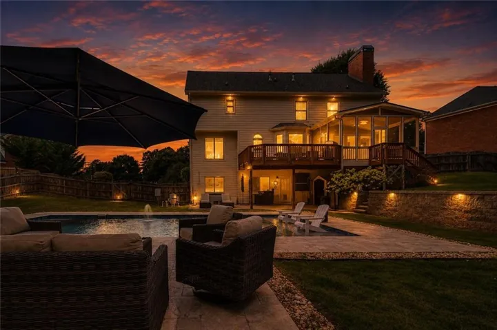 Expansive exterior featuring a swimming pool with water feature, paver patio, wood deck, screened porch, and stone retaining wall
