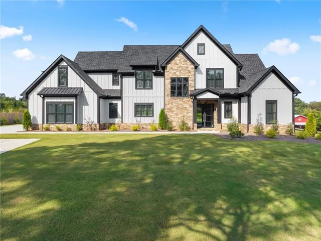 Modern farmhouse exterior with board and batten siding, stone facade accents, dark-frame windows, and a black shingle roof