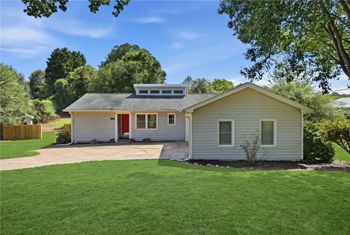 Ranch-style exterior with light gray siding, a red entry door, a clerestory window feature, and a paved driveway