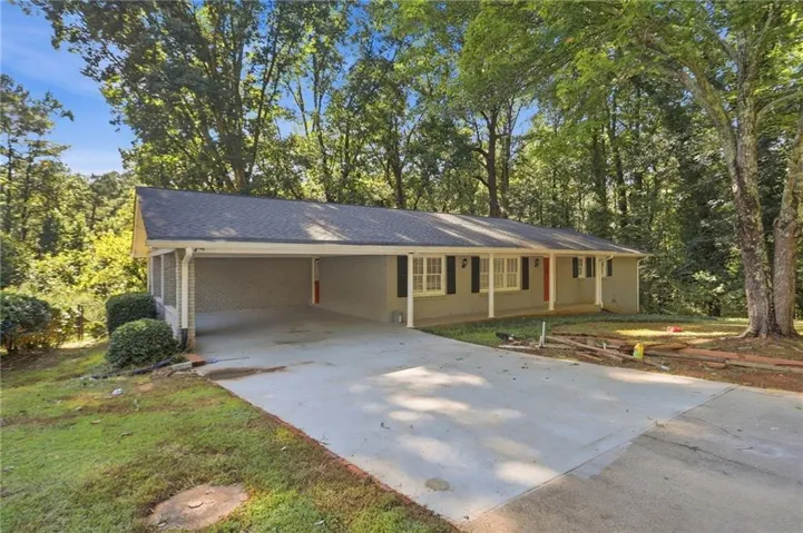Single-story exterior with a covered carport, concrete driveway, and mature landscaping