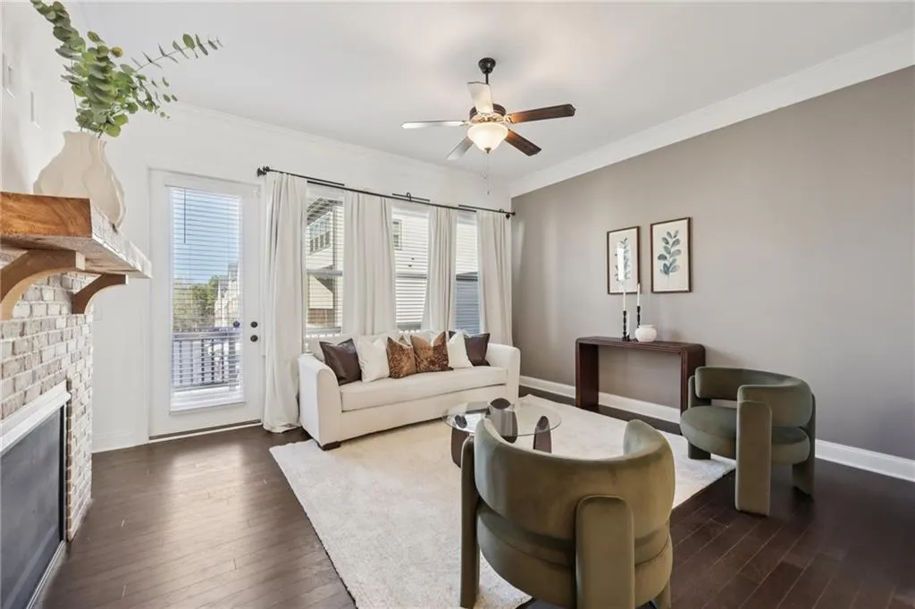 Living area featuring ornamental molding, ceiling fan, dark wood-style flooring, and a brick fireplace