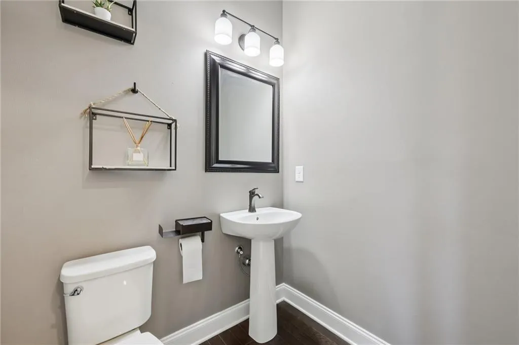 Half bath featuring baseboards and dark wood-style flooring