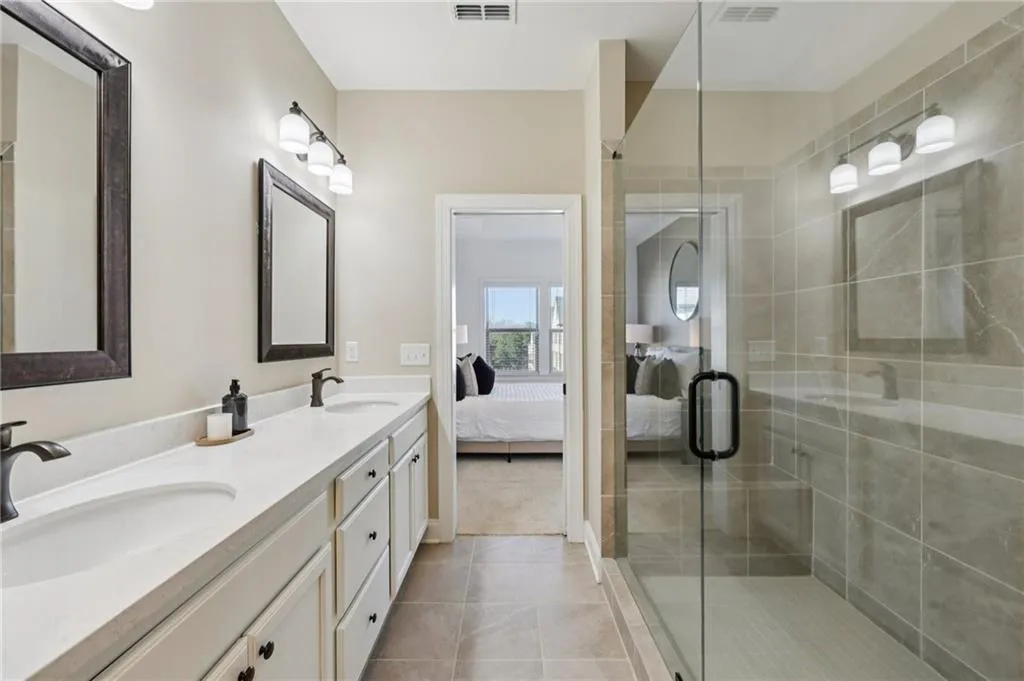 Bathroom with connected bathroom, double vanity, a shower stall, and light tile patterned flooring
