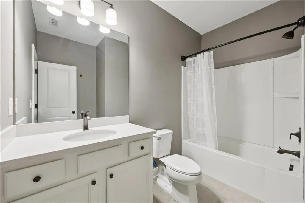 Bathroom with vanity, shower / tub combo, and light tile patterned floors