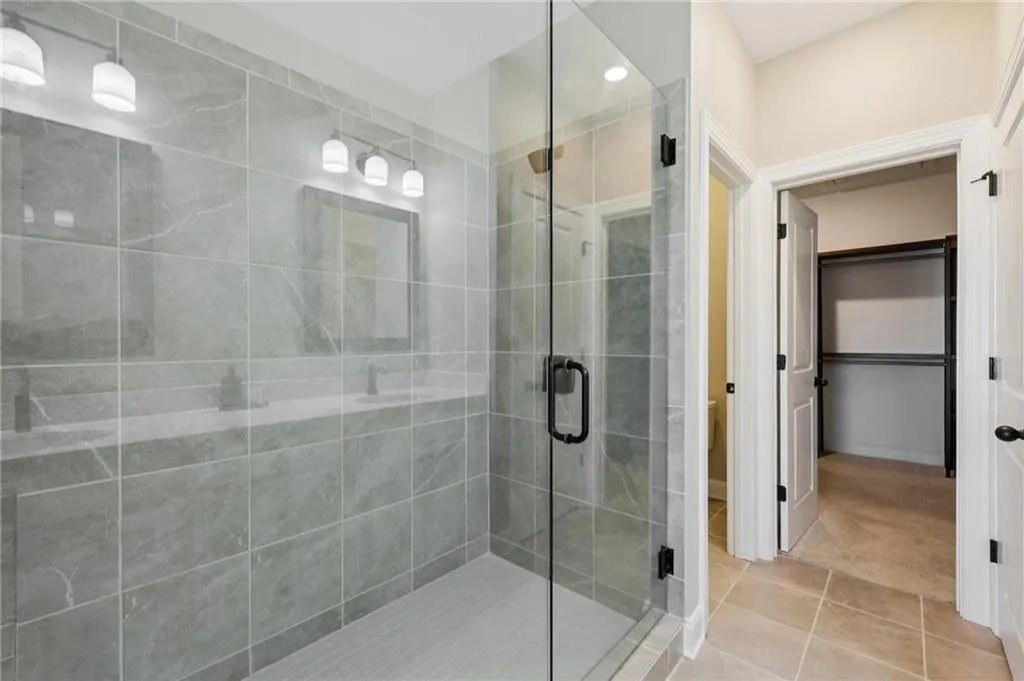 Full bath featuring a shower stall, tile patterned flooring, a spacious closet, and recessed lighting