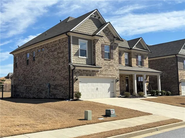 Two-story brick exterior featuring a covered front porch, an attached two-car garage, and multiple gabled rooflines