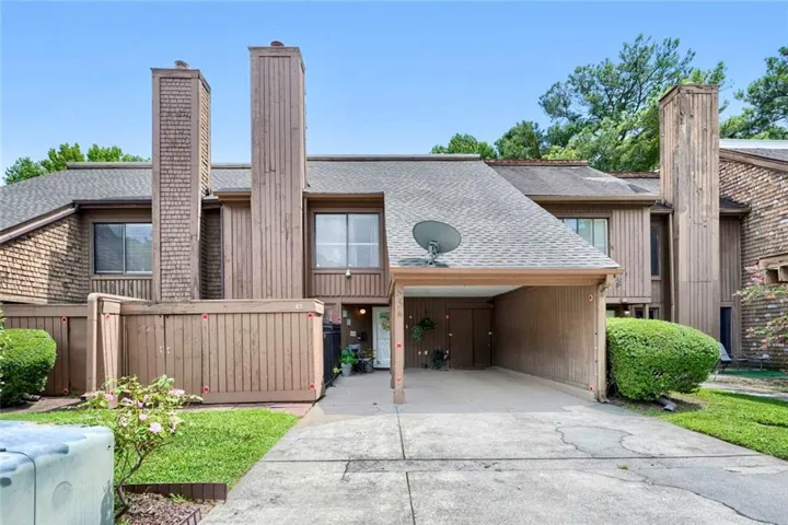Multi-level exterior with shingle siding, a covered carport, and multiple prominent chimney structures