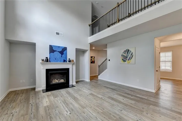 Spacious living area featuring a vaulted ceiling and wood-finish flooring