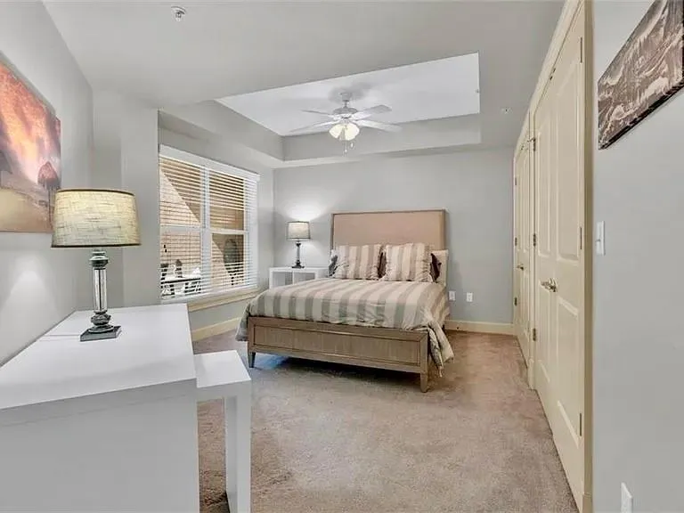 Bedroom featuring a tray ceiling, light carpet, and ceiling fan