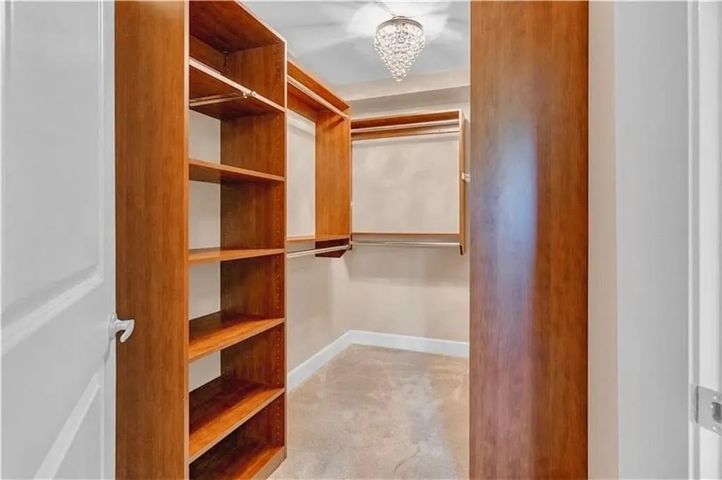 Walk in closet with a chandelier and carpet