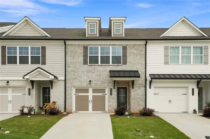 Exterior featuring brick and siding facade, dormer windows, covered entryways, and attached garages