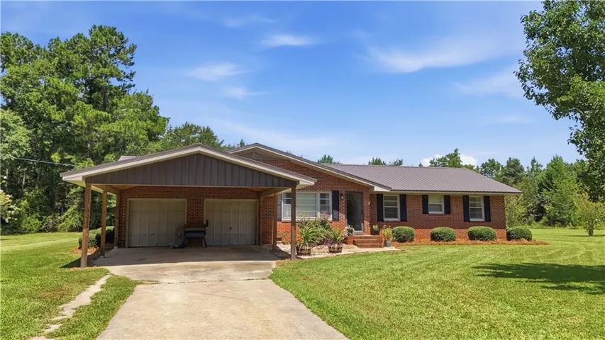 Brick exterior residence featuring a metal roof and an attached carport