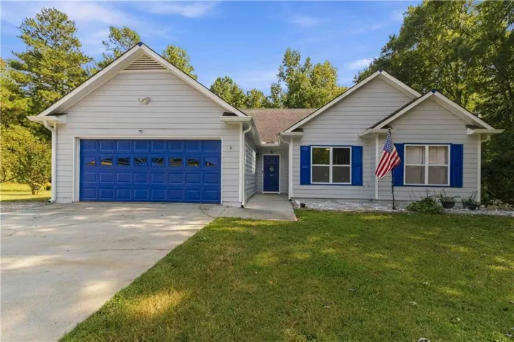 Single-story residence featuring light gray siding, a prominent blue garage door, blue decorative shutters, a covered entry, and a concrete driveway