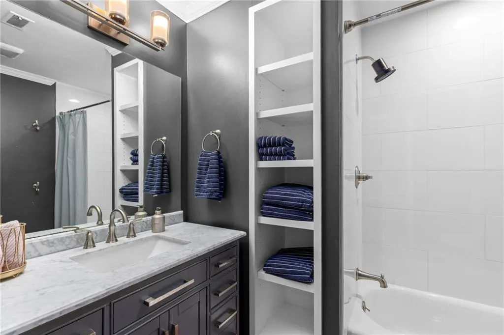 Full bathroom featuring shower / bath combo with shower curtain, vanity, and crown molding