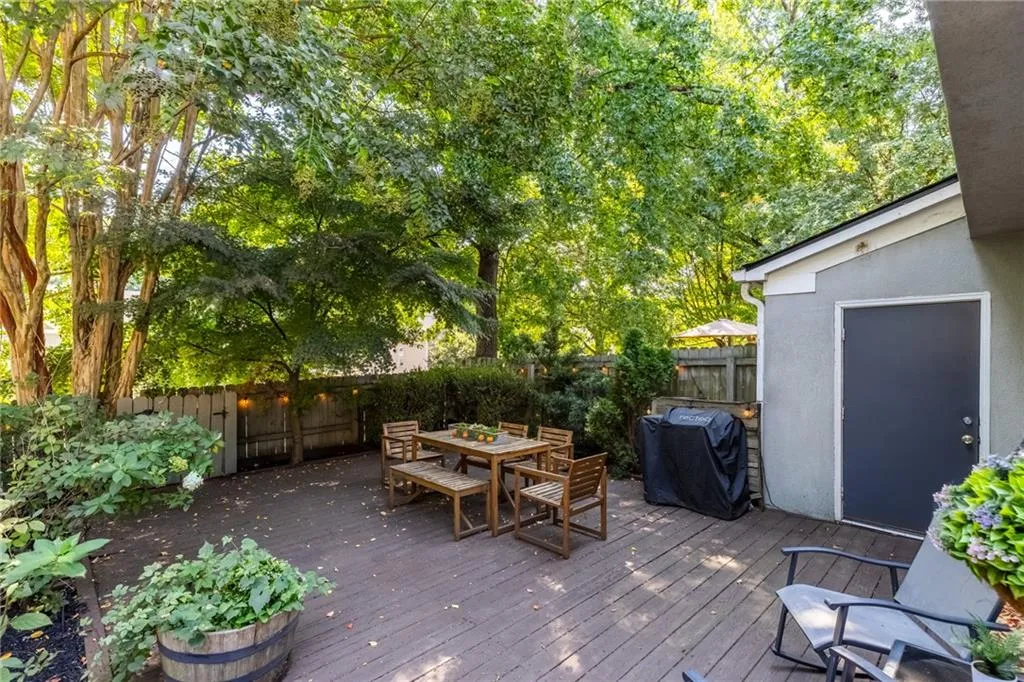 Wooden terrace with outdoor dining area, a fenced backyard, and a grill
