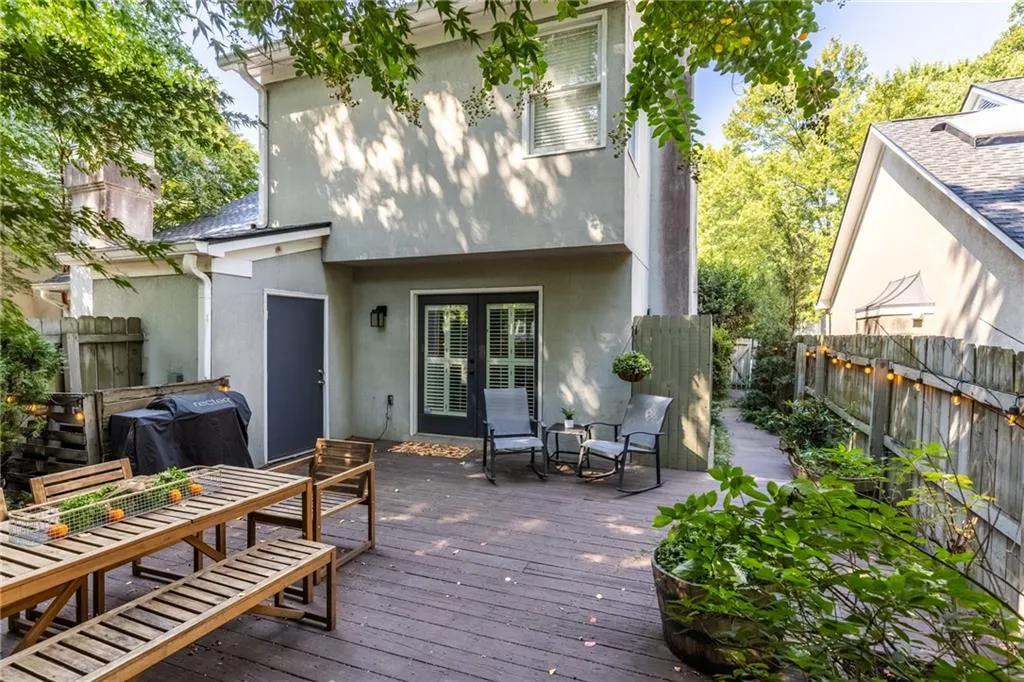 Rear view of property with a fenced backyard, stucco siding, outdoor dining area, and a wooden deck