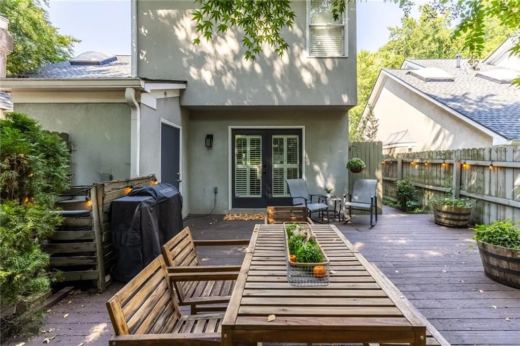 Back of property with stucco siding, a wooden deck, and french doors