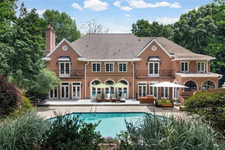 Elegant brick estate with a beautifully landscaped backyard and pool, creating a private outdoor retreat.