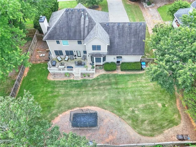 Expansive backyard featuring a large green lawn, a multi-level deck with white railings, and mature perimeter trees