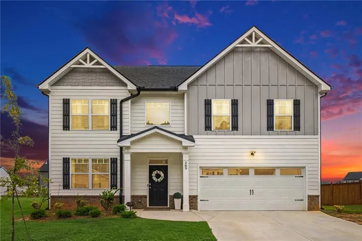 Two-story residence featuring white siding, a two-car garage, and multiple gabled rooflines