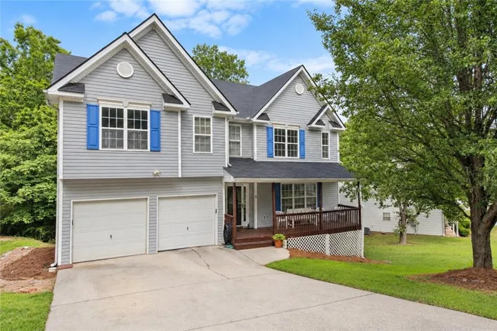 Two-story residence featuring light gray siding, dark shingle roof, and blue window shutters