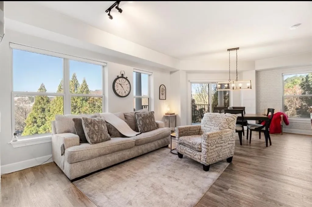 Living area with track lighting, a notable chandelier, wood finished floors, and baseboards