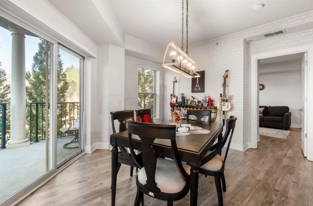 Dining area featuring light wood finished floors, visible vents, brick wall, and baseboards
