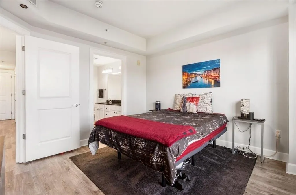 Primary Suite bedroom featuring light wood-type flooring, baseboards, and connected bathroom