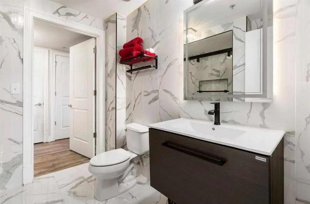 Bathroom with vanity, stone wall, tile walls, toilet, and marble finish floor