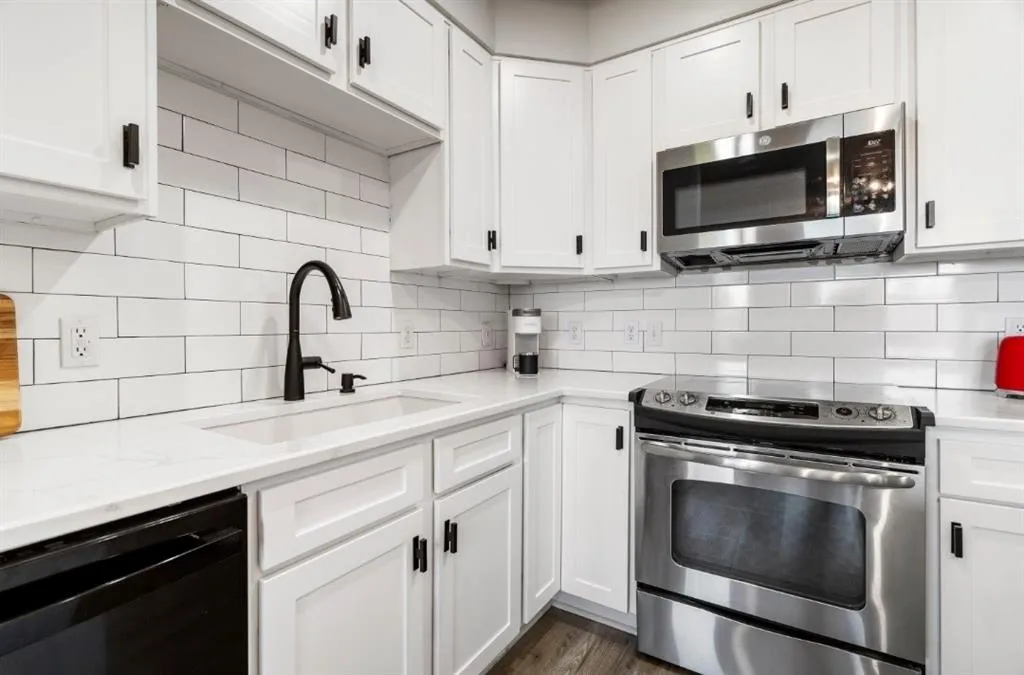 Kitchen featuring a sink, stainless steel appliances, backsplash, and white cabinets