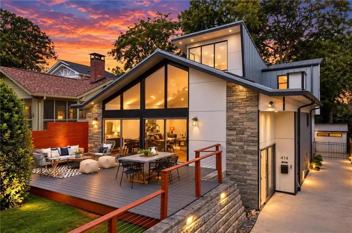 Modern architectural design featuring expansive glass windows, a spacious multi-level deck, and stone exterior accents
