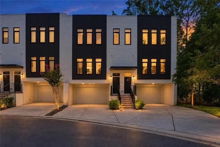 Modern exterior featuring a two-tone facade, prominent black-framed windows, integrated garage, and a concrete driveway