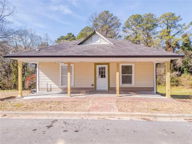 Siding exterior with a covered porch, brick paver walkway, and a gabled roofline