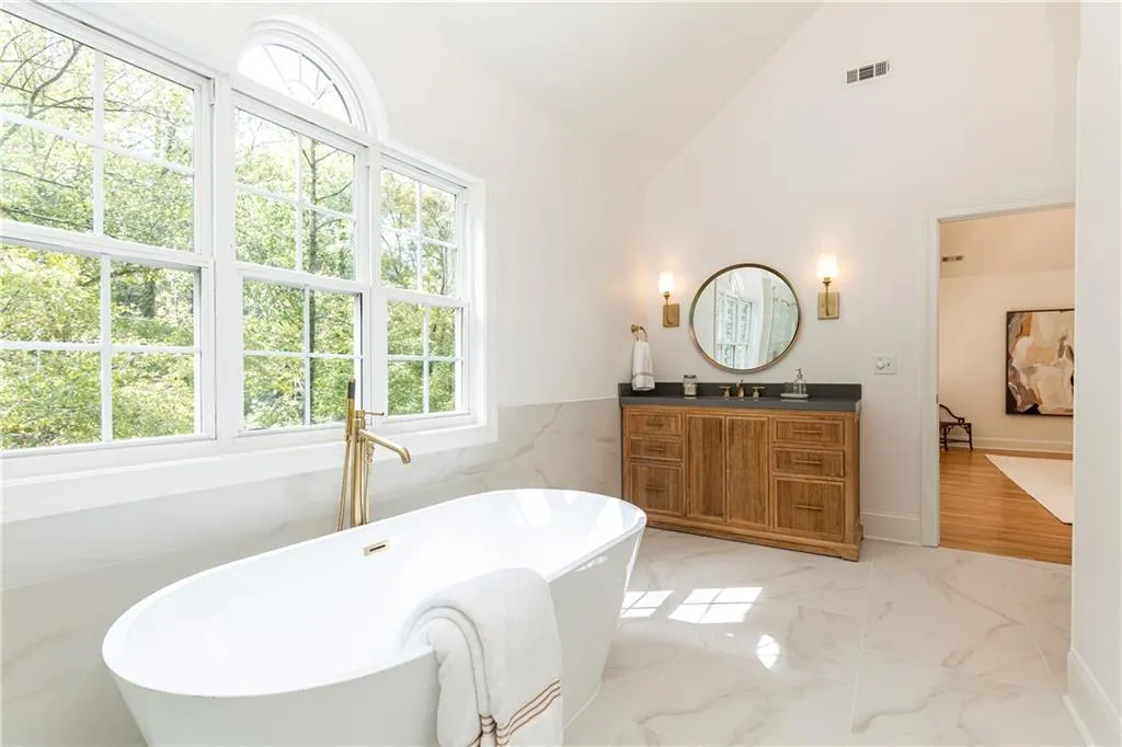 Brass accents throughout primary bathroom with plumbing fixtures, lighting, hardware and mirrors