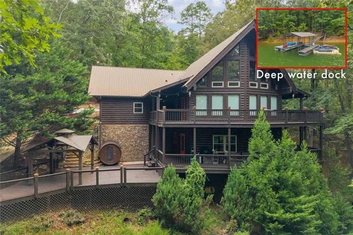 Log cabin exterior featuring a metal roof, stone foundation, multi-level decks, and a prominent gable with large windows