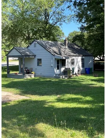 Back of property with a yard, a chimney, and a shingled roof