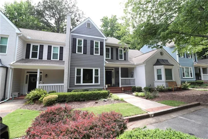 Exterior featuring gray siding, white brick, black shutters, and an inviting front porch