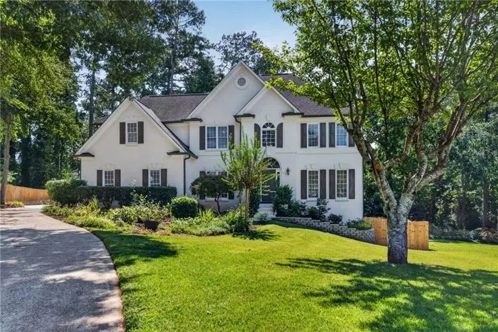 Two-story exterior with white siding, dark shutters, and a gabled roof