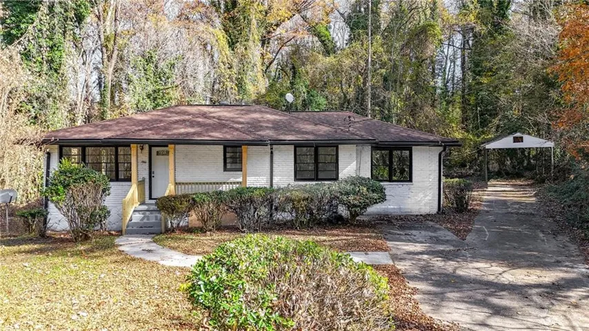 Ranch-style house with a shingled roof, brick siding, covered porch, and a carport