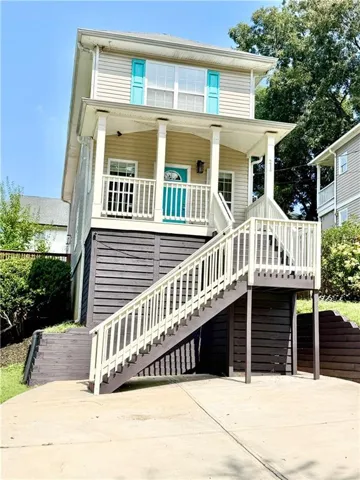 Two-story residence with siding exterior, upper-level windows with contrasting shutters, covered entry porch, and exterior staircase with railing